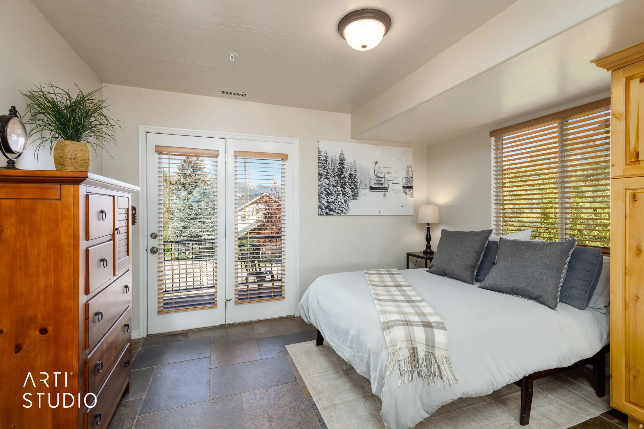 French doors with integrated blinds, stone tile flooring, and a flush mount ceiling light. Doors open to North-facing balcony.
