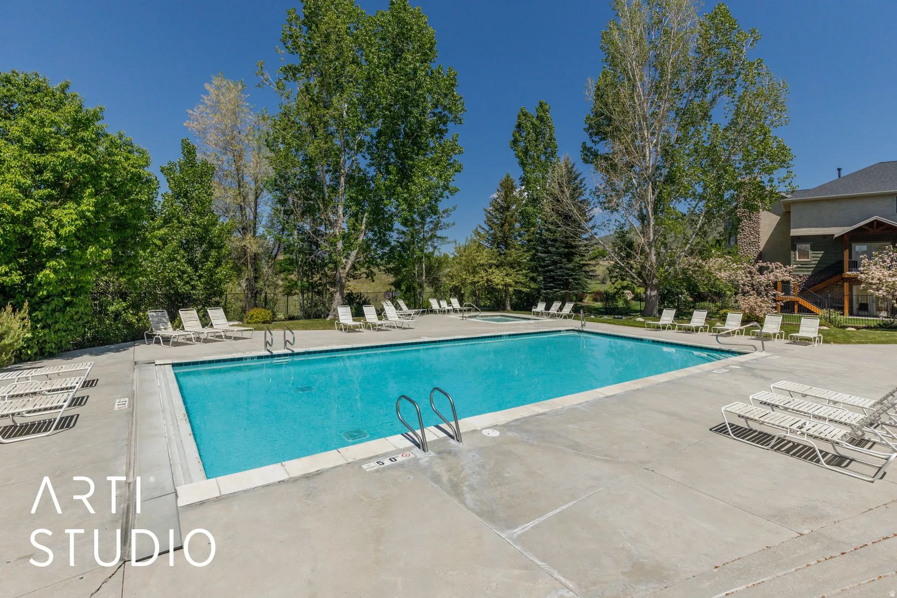 Community swimming pool with surrounding concrete decking and mature trees