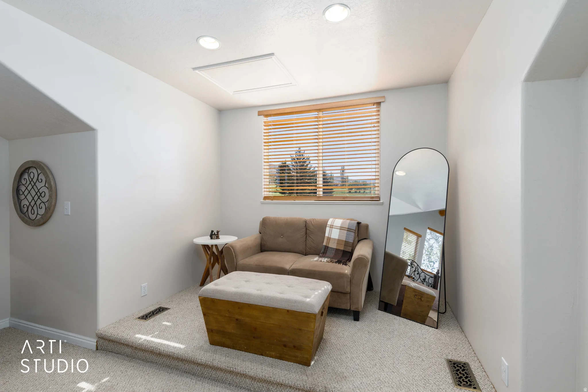 Recessed lighting illuminates a raised carpeted seating area with a window featuring wood blinds. This is in the primary bedroom on the 2nd level.