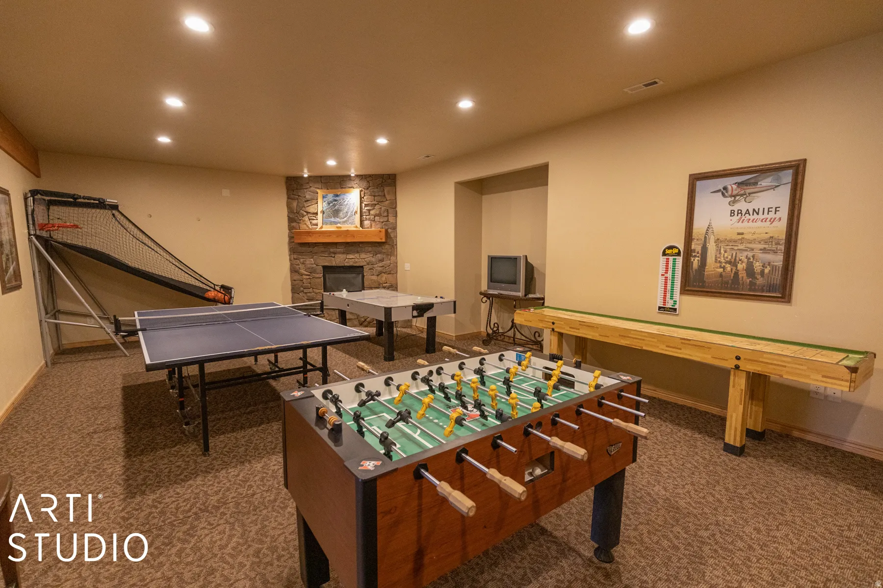 Expansive entertainment space featuring recessed lighting, a stone-clad fireplace with a wood mantle, and textured carpeting