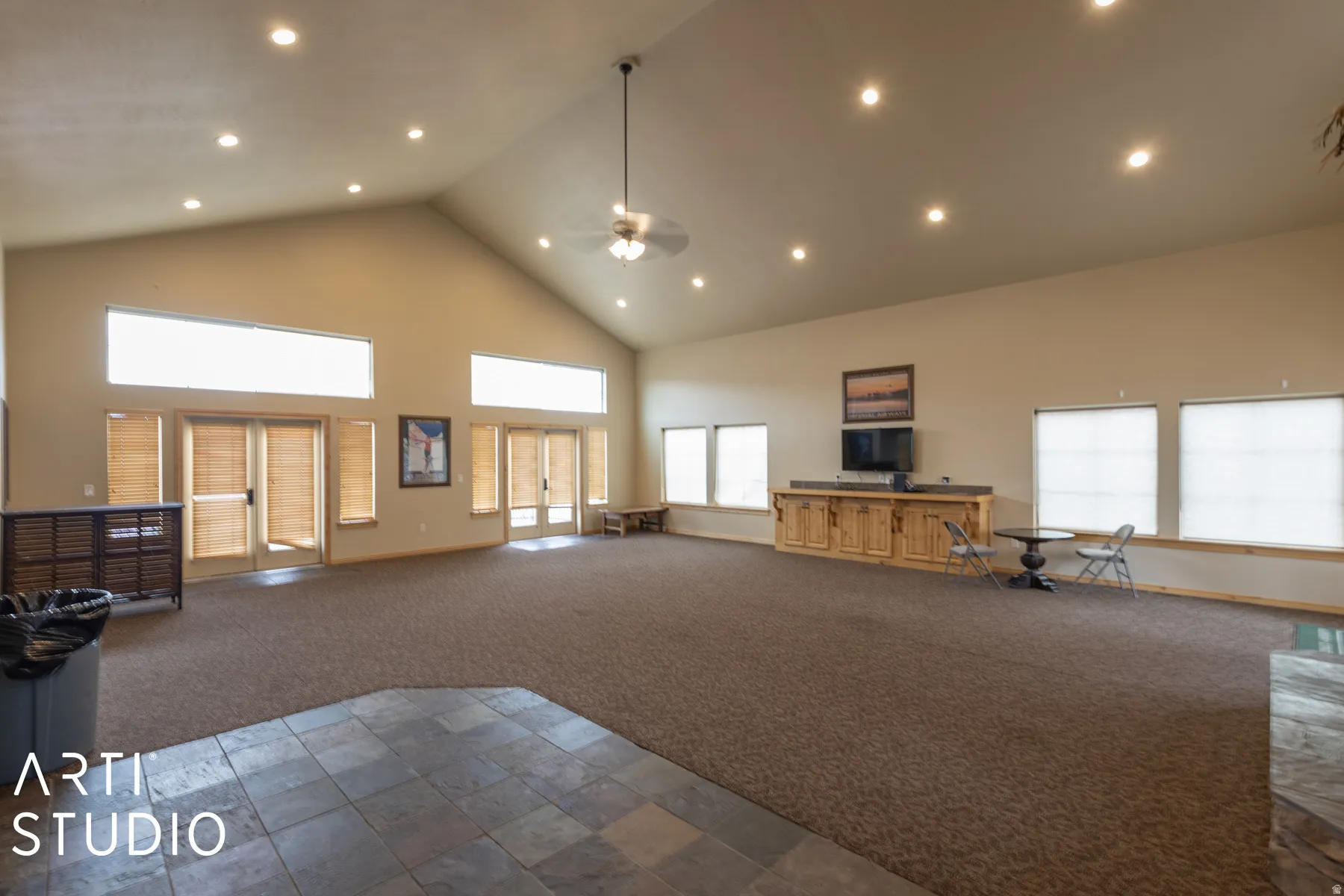 Vaulted ceiling with recessed lighting, ceiling fan, multiple windows with blinds, built-in cabinetry, and tile flooring