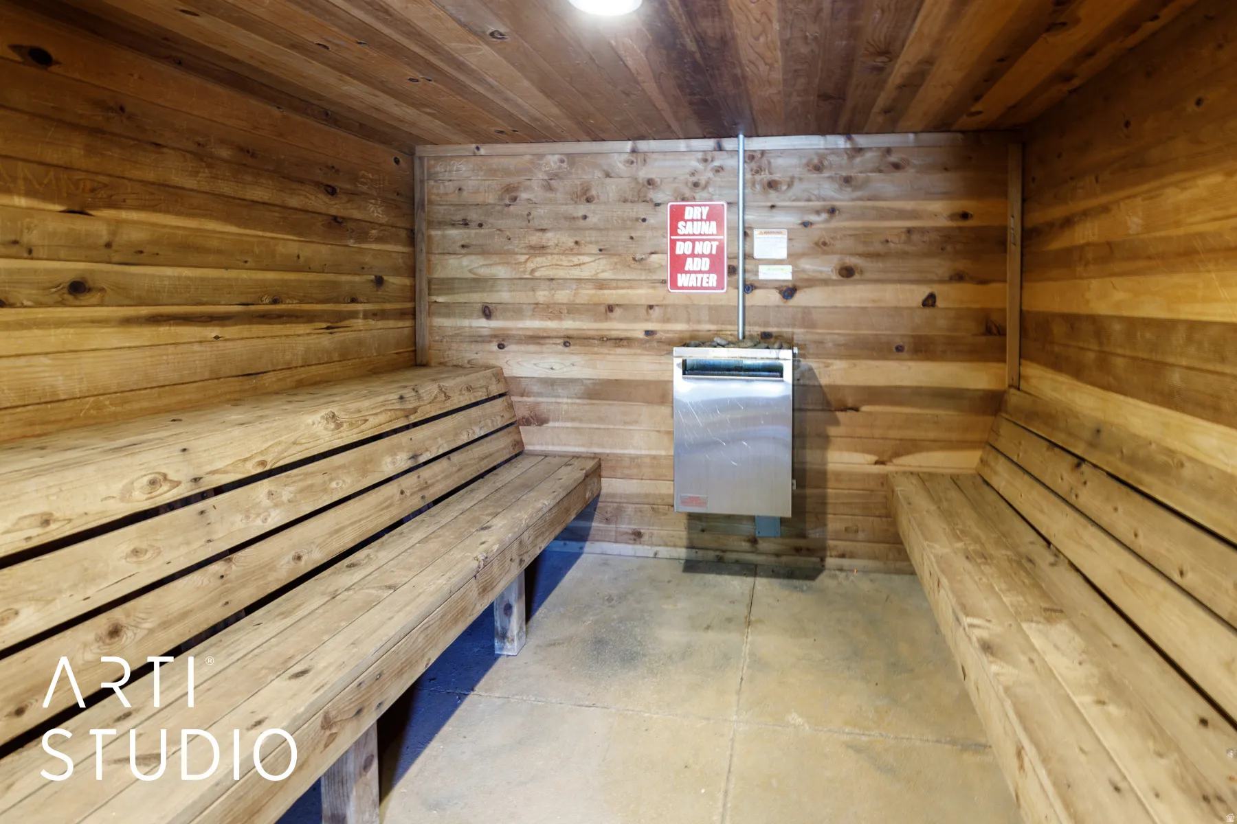 Wood-paneled sauna featuring two built-in wooden benches and a concrete floor