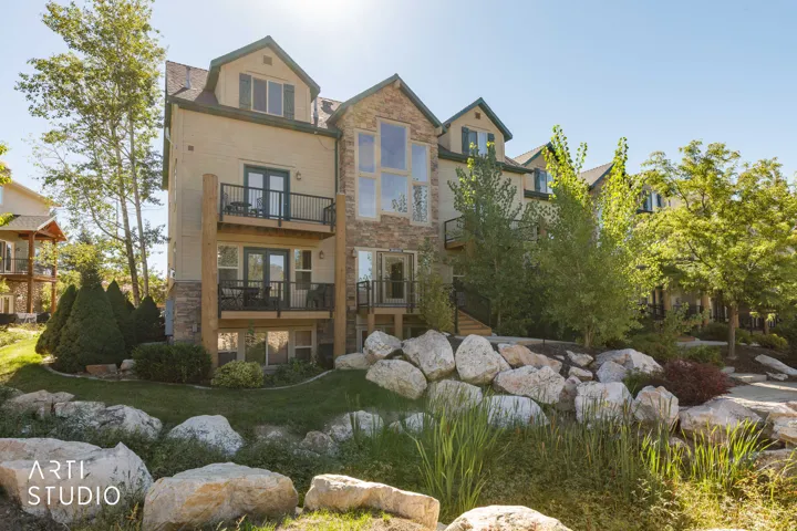 Unit 610 has the top-left balcony. Stone and siding exterior with multiple balconies, large windows, dormer windows, and a tiered rock garden