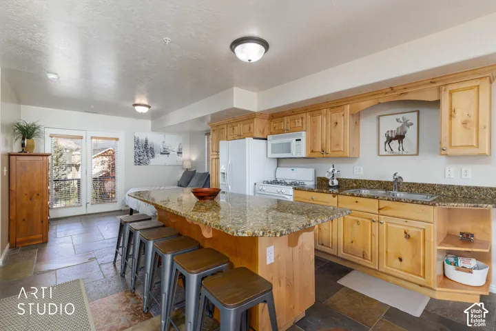 Kitchenette with wood-finish cabinetry, granite-style countertops, and a full suite of appliances