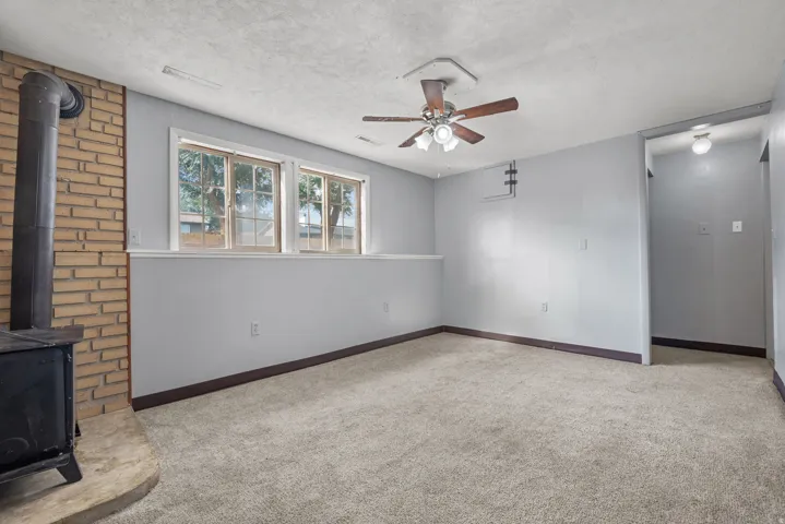 Carpeted room with a wood-burning stove and brick surround