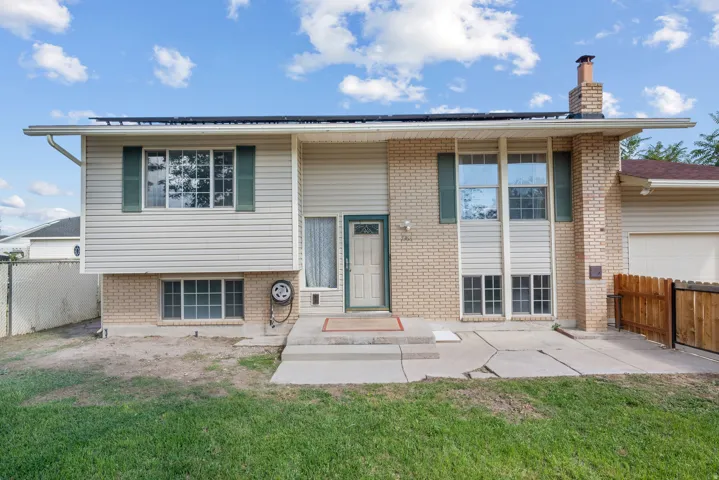 Split-level residence featuring light-colored siding, brick accents, and a front entry