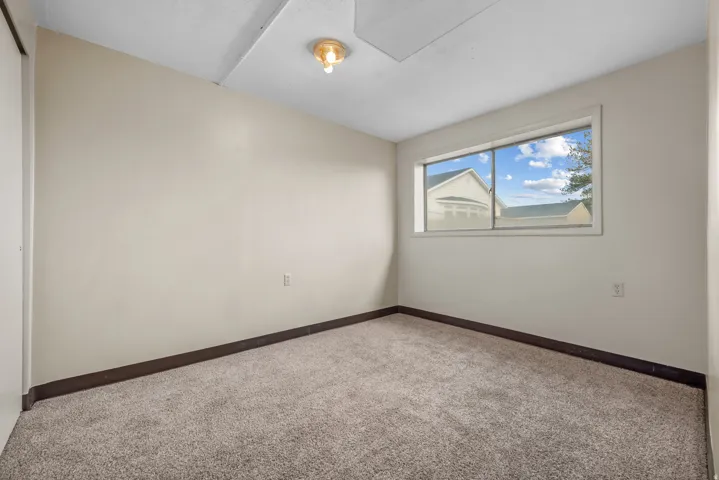 Wall-to-wall carpeting with light-toned walls, featuring a window and a ceiling-mounted light fixture