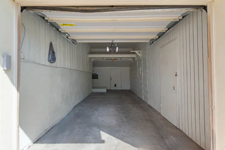 Attached garage space with concrete flooring, vertical paneling, and an interior access door