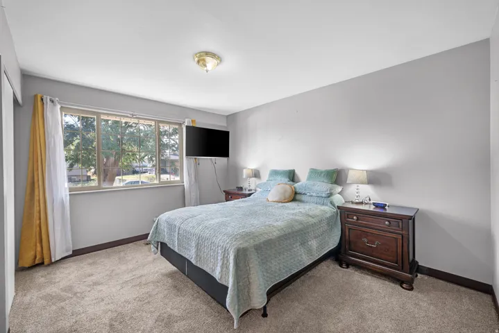 Carpeted flooring, neutral wall tones, and a multi-pane window
