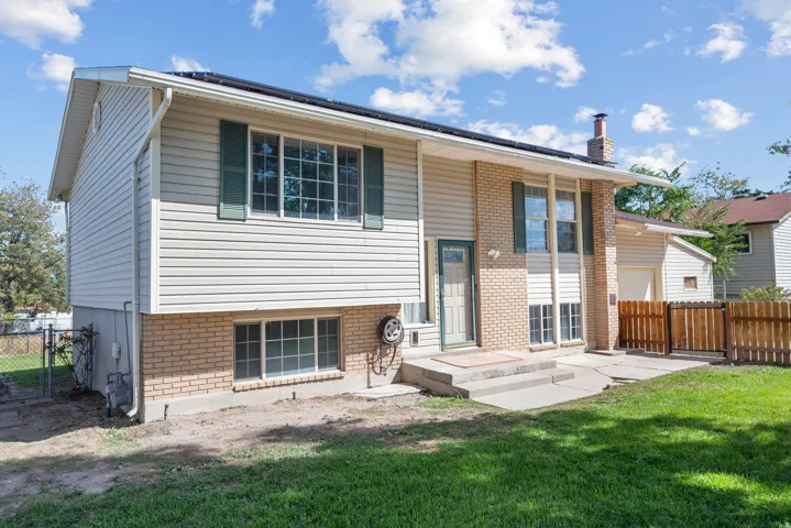 Split-level exterior featuring light-colored siding, brick accents, and green window shutters
