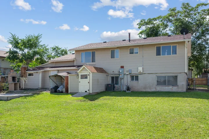 Expansive green lawn, detached storage shed, exterior brick oven, and perimeter fencing