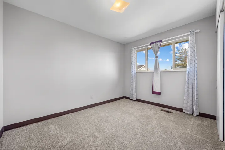 Plush gray carpeting, light gray wall paint, and a white framed window