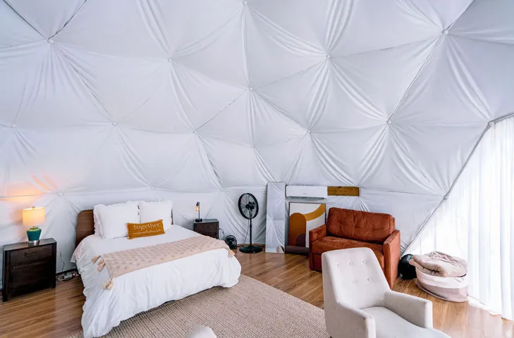 Geodesic dome interior featuring a wood-finish flooring, white fabric walls, and an integrated air conditioning unit