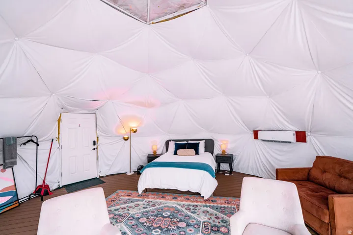 Geodesic dome structure with interior white fabric paneling, wood-finish flooring, and a wall-mounted air conditioning unit