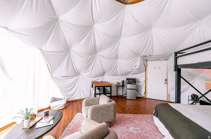 Geodesic dome interior featuring a paneled ceiling, wood-finish flooring, and white paneled door