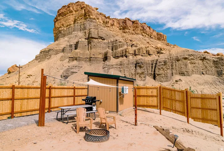Enclosed outdoor space featuring a wood fence, a fire pit, and string lighting