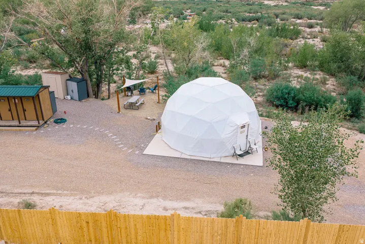 Geodesic dome structure on a gravel lot with a wooden privacy fence