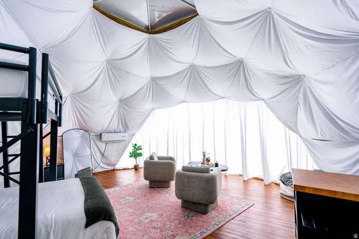 Geodesic dome interior featuring a white fabric ceiling, wood-finish flooring, and expansive window treatments