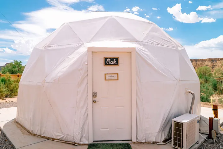Geodesic dome structure featuring a white exterior and a white entry door