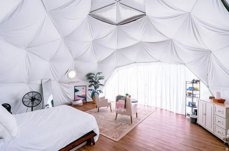 Geodesic dome interior with wood-finish flooring, white fabric walls, and a built-in upper skylight