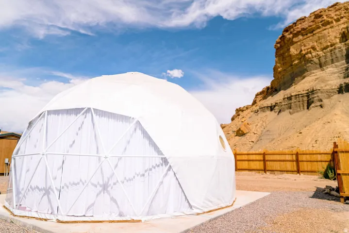 Geodesic dome structure with a white exterior, round window, and a gravel perimeter
