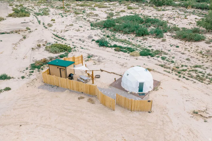 Private fenced outdoor area featuring a geodesic dome and a separate utility structure with a green roof