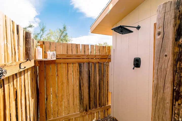 Outdoor shower featuring a matte black rain shower head and a wood-slat enclosure