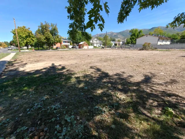 Expansive cleared lot with surrounding mature trees and mountain backdrop