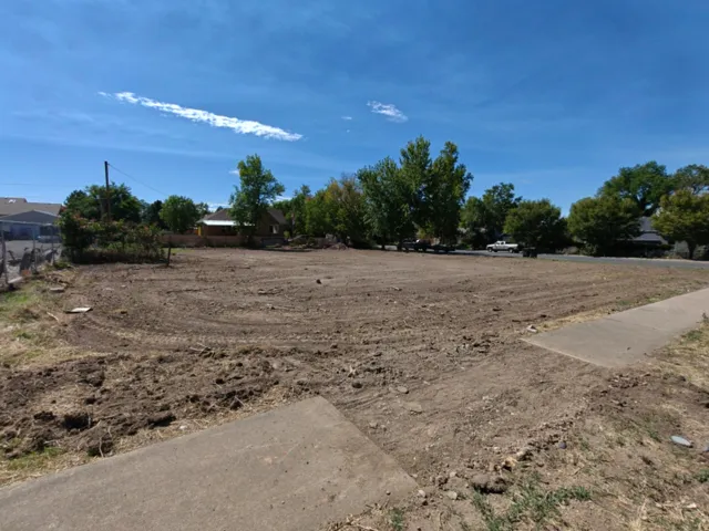 Cleared land parcel featuring established concrete curbing and a paved sidewalk