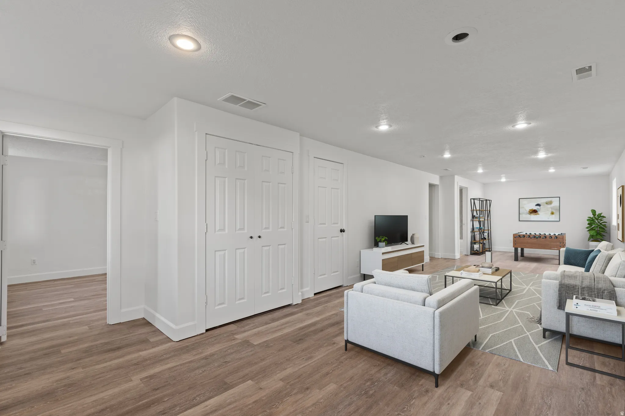Wood-finish flooring throughout, recessed lighting, and white paneled doors