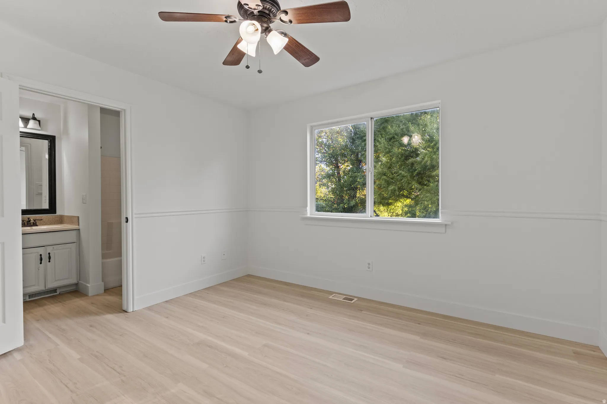 Light wood-finish flooring, a ceiling fan with integrated lighting, and a window with exterior views