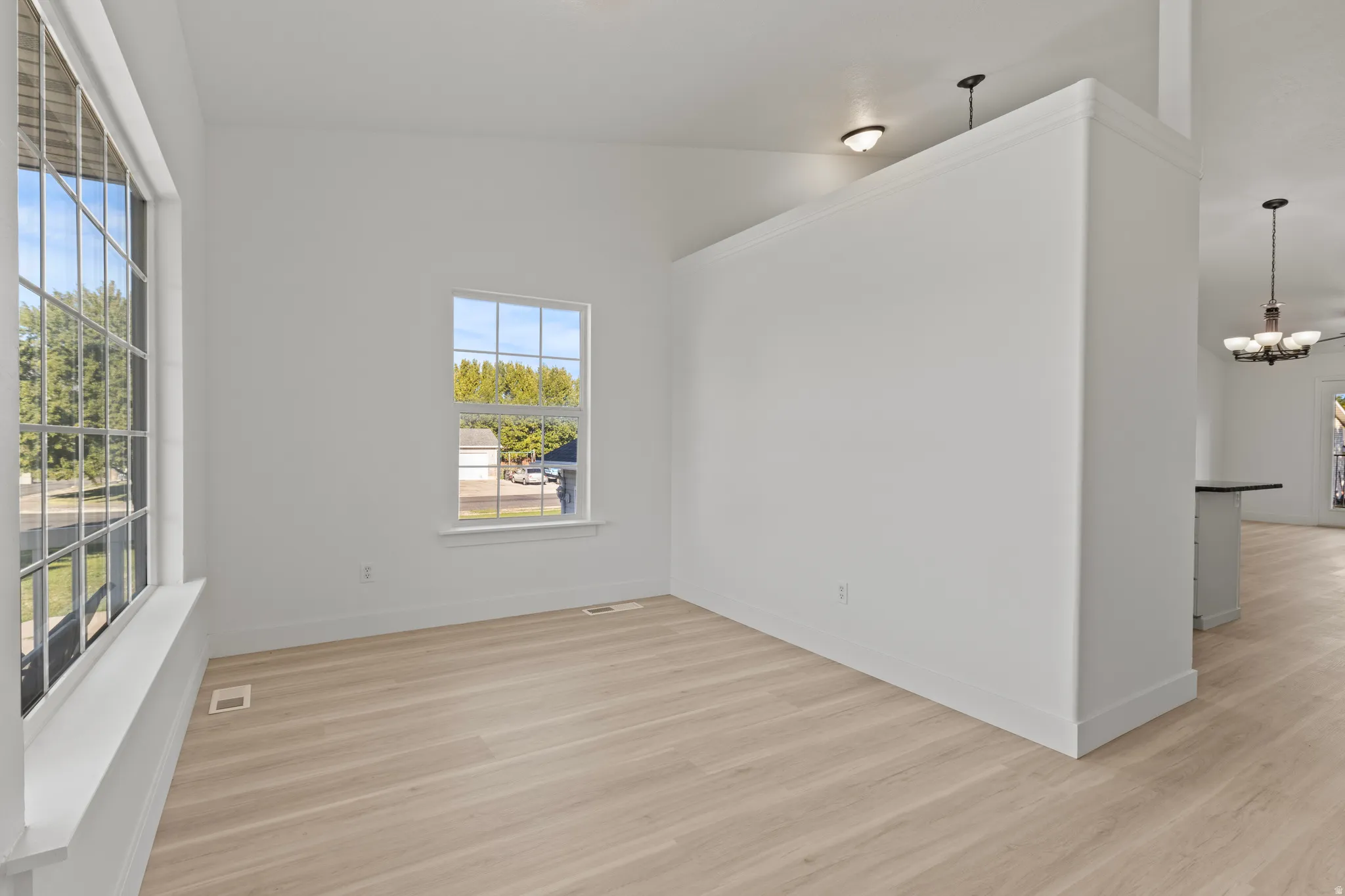 Spacious room with light wood-finish flooring, white walls, and a large multi-pane window