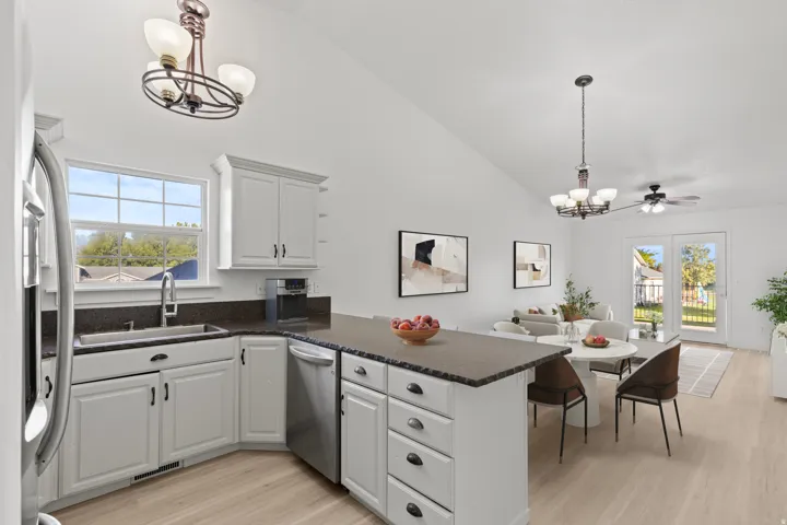 White cabinetry with dark hardware, stainless steel appliances, dark countertops, and wood-finish flooring