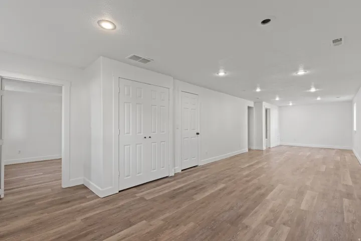 Expansive room featuring wood-finish flooring, recessed lighting, and multiple paneled doors