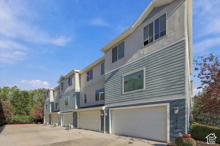 Multi-level exterior featuring horizontal siding, smooth-finish stucco, large windows, and attached garage bays