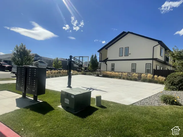 Paved court area with a basketball hoop, surrounded by landscaped grass and ornamental grasses