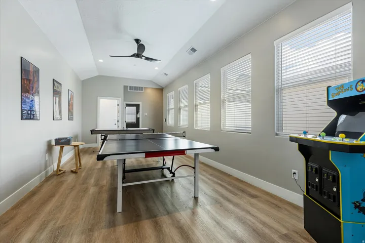 Vaulted ceiling with a ceiling fan, recessed lighting, wood-finish flooring, multiple windows with blinds, and white trim throughout
