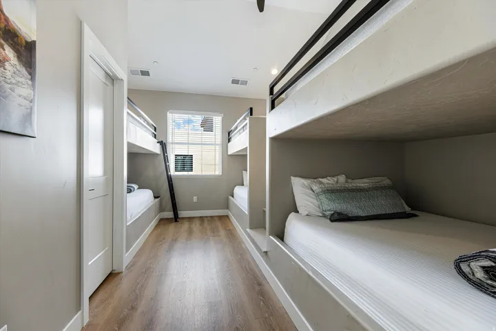 Recessed lighting, wood-finish flooring, and built-in bunk beds with black metal railings