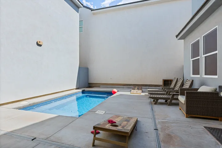 Private outdoor space featuring a rectangular swimming pool, concrete patio, and stucco exterior walls