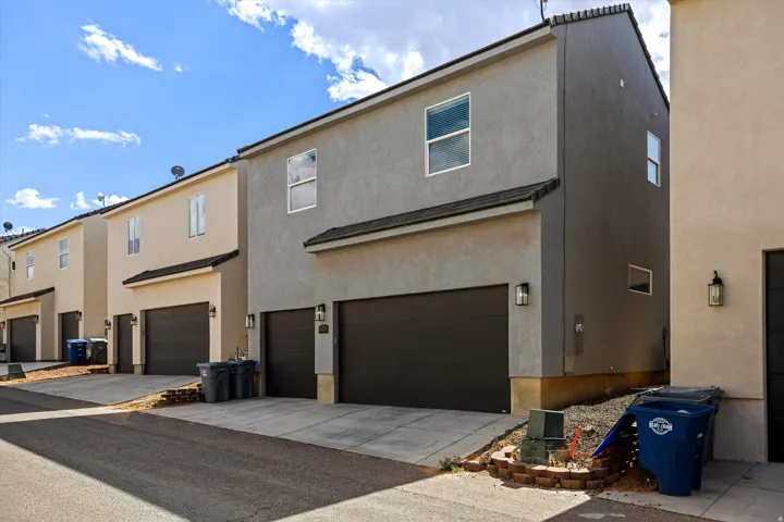Stucco exterior featuring multiple windows, dark roof tiles, and exterior light fixtures