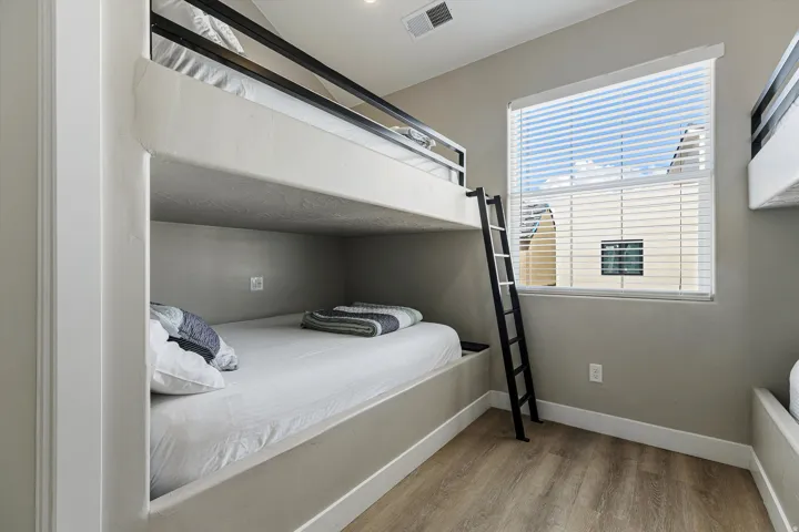 Built-in bunk beds with integrated ladder, window with blinds, and wood-finish flooring