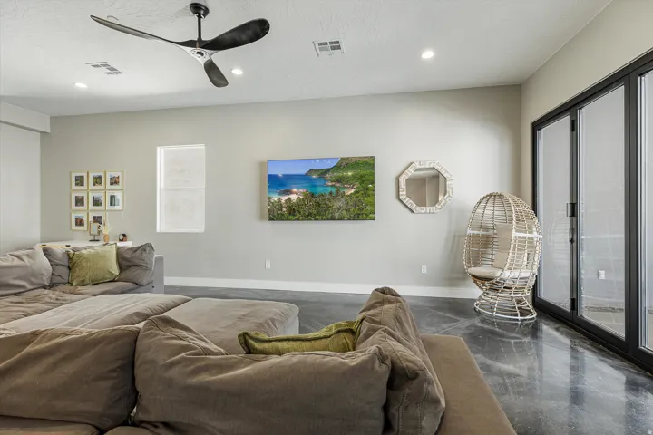 Polished concrete flooring with a modern ceiling fan, recessed lighting, and expansive folding glass doors