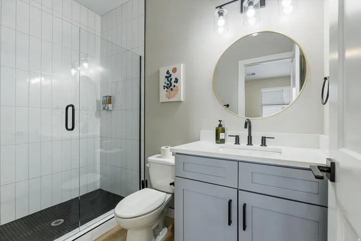 Glass-enclosed shower with subway tile surround and dark tiled floor