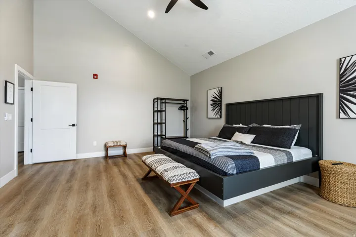 High vaulted ceilings, wood-finish flooring, white paneled doors with matte black hardware, and a ceiling fan