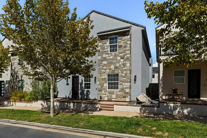Stucco and stone facade with a dark gray trim, featuring a dark entry door and multi-pane windows