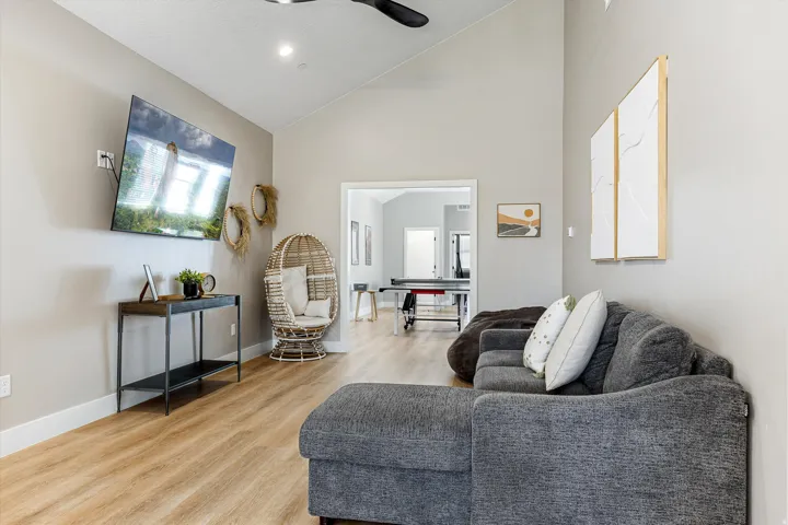 Vaulted ceilings, wood-finish flooring, recessed lighting, ceiling fan, and an open doorway leading to another room