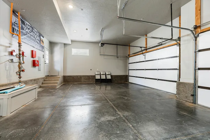 Spacious garage featuring a concrete floor, multiple overhead garage doors, recessed lighting, and an exterior access door