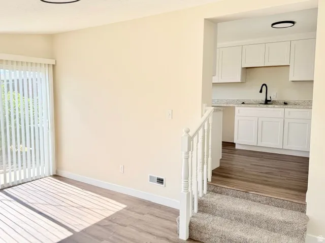 Wood-finish flooring with vertical blinds and a white railing
