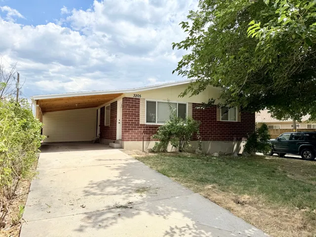 Brick exterior with light-colored siding, concrete driveway, and covered carport with wood-finish ceiling