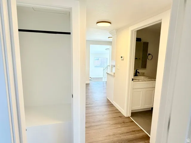 Hallway with wood-finish flooring, recessed lighting, and a built-in closet